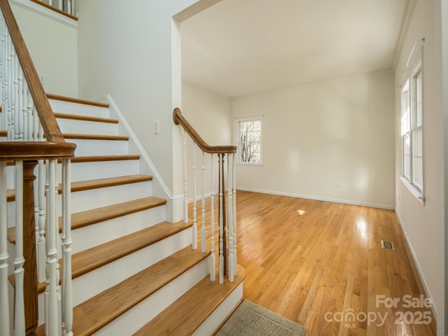 stairway with hardwood / wood-style flooring and crown molding