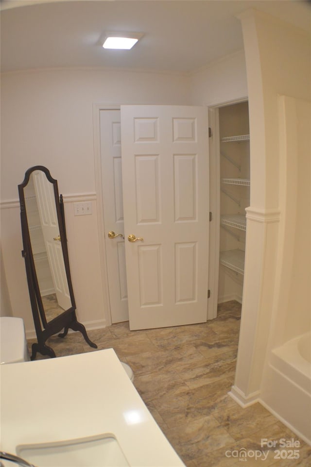 interior space featuring ornamental molding, wood-type flooring, and a tub to relax in