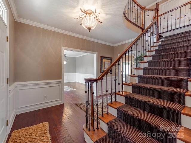 stairs with an inviting chandelier, ornamental molding, and wood-type flooring