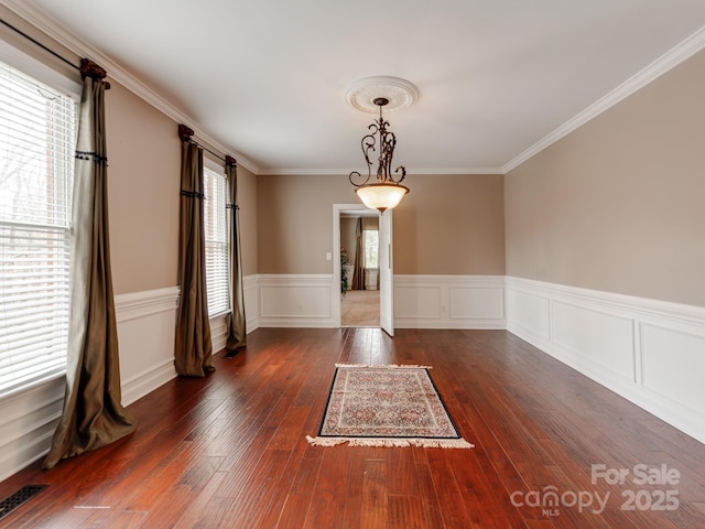 empty room featuring dark hardwood / wood-style flooring, plenty of natural light, and ornamental molding