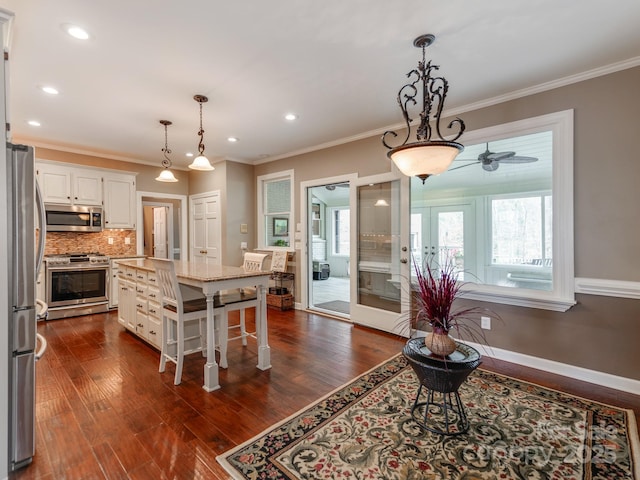 kitchen with a breakfast bar, a center island, stainless steel appliances, light stone countertops, and white cabinets