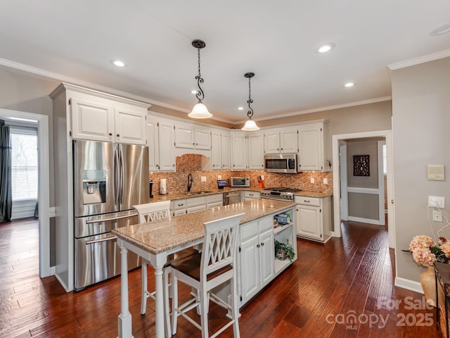 kitchen featuring appliances with stainless steel finishes, white cabinetry, sink, a center island, and light stone countertops