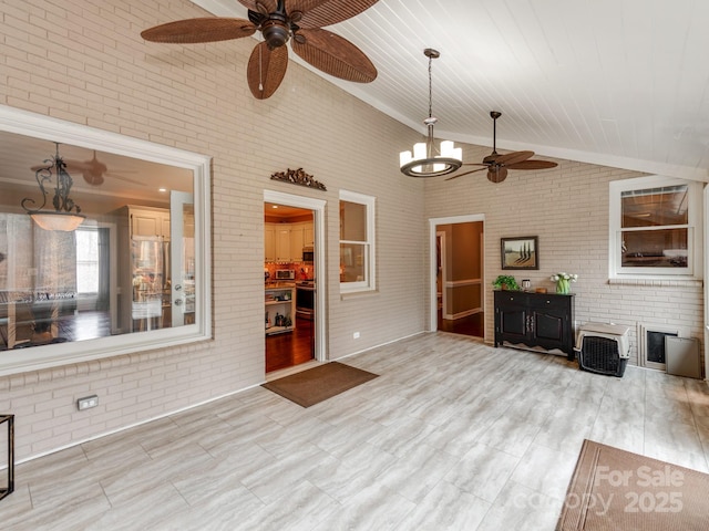 unfurnished living room featuring brick wall, high vaulted ceiling, and ceiling fan