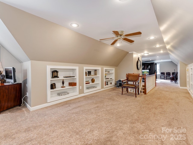 interior space featuring built in shelves, vaulted ceiling, light colored carpet, and ceiling fan