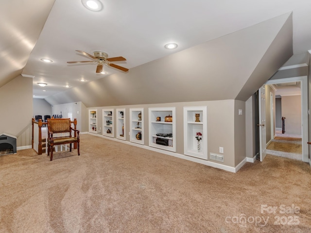 interior space featuring ceiling fan, light colored carpet, vaulted ceiling, and built in features