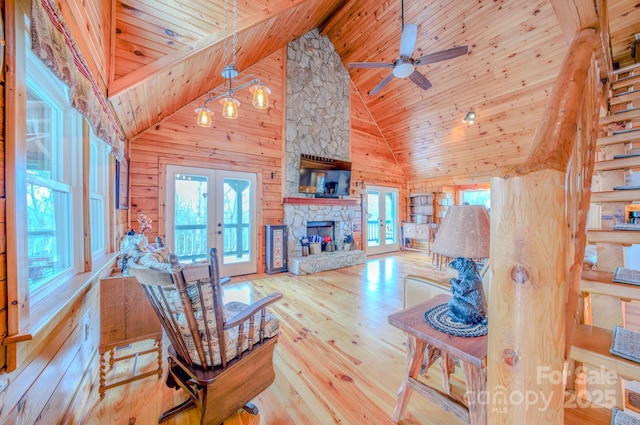 living room featuring wooden walls, a fireplace, wooden ceiling, french doors, and light wood-type flooring