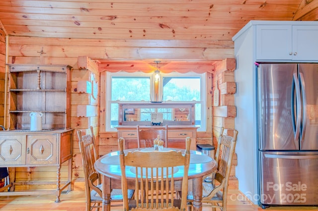 dining room with wooden walls, light wood-type flooring, and wooden ceiling