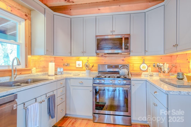 kitchen with stainless steel appliances, light stone countertops, and sink