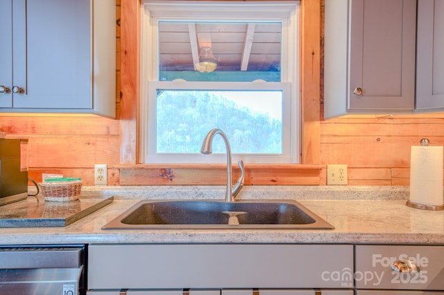 kitchen featuring light stone counters, sink, and dishwashing machine