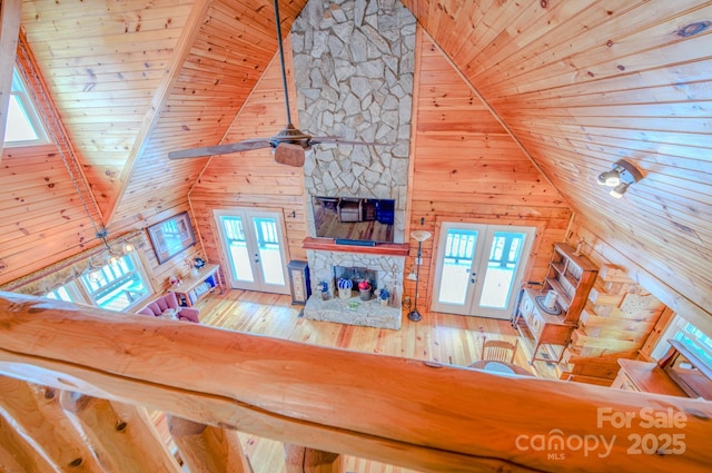 unfurnished living room with hardwood / wood-style floors, wooden ceiling, a fireplace, and french doors