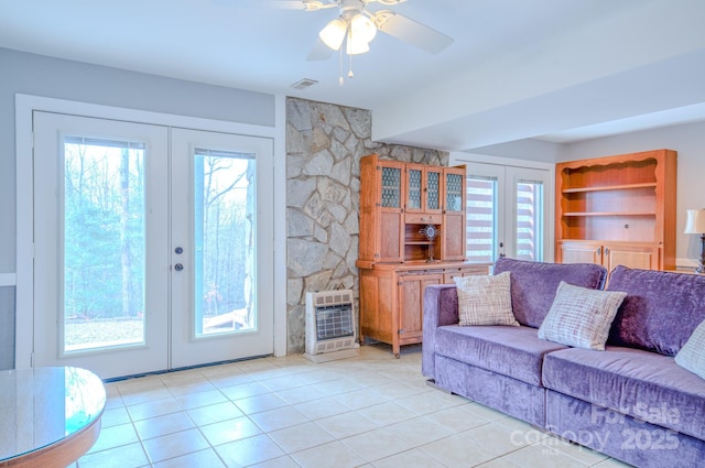 tiled living room featuring heating unit, built in shelves, a wealth of natural light, and french doors