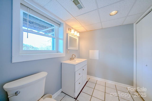 bathroom with vanity, a drop ceiling, tile patterned floors, and toilet