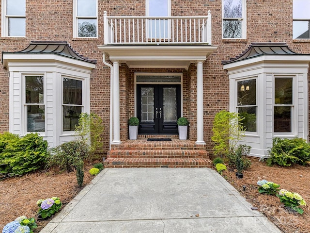 entrance to property featuring french doors, brick siding, and a standing seam roof