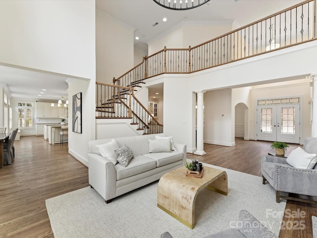 living room with stairway, wood finished floors, baseboards, and ornamental molding