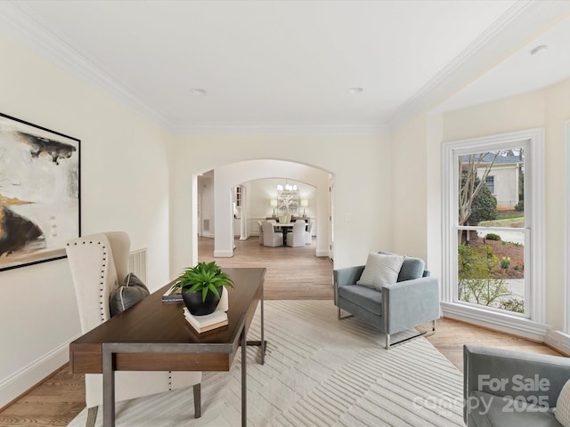 home office with light wood-style floors, arched walkways, and ornamental molding