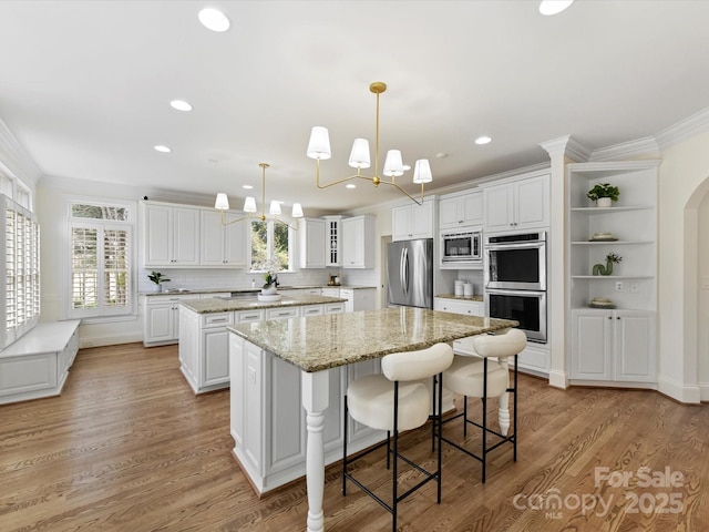 kitchen featuring stainless steel appliances, ornamental molding, a center island, and white cabinetry