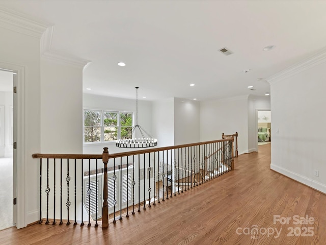 hall featuring crown molding, baseboards, recessed lighting, an inviting chandelier, and wood finished floors