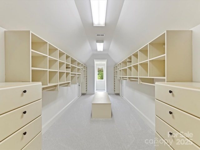 walk in closet with visible vents, light carpet, and vaulted ceiling