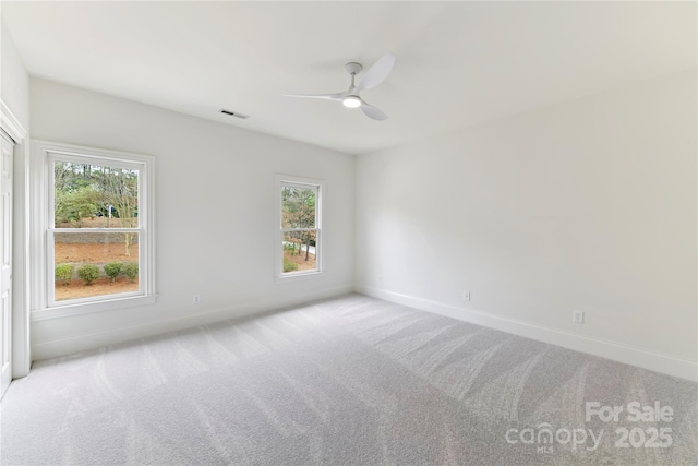 carpeted spare room with visible vents, plenty of natural light, and baseboards