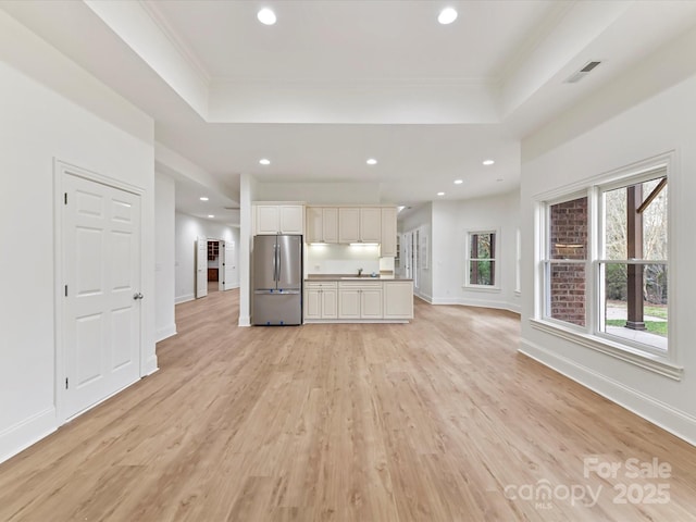 kitchen with a tray ceiling, recessed lighting, freestanding refrigerator, light wood-style floors, and open floor plan