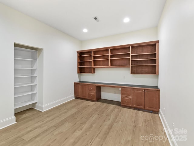 unfurnished office featuring recessed lighting, baseboards, built in desk, and light wood finished floors