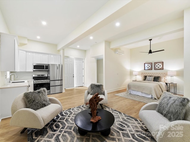 bedroom with light wood finished floors, beamed ceiling, freestanding refrigerator, and a sink