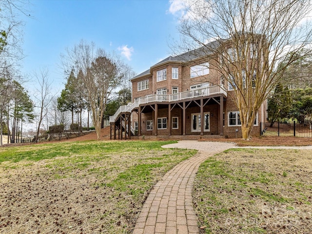 rear view of house with stairway, fence, a lawn, and brick siding