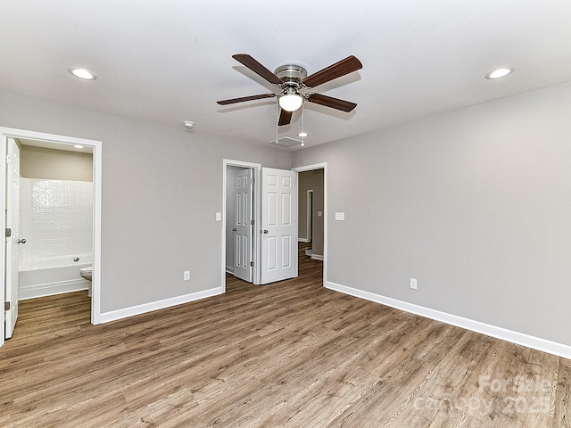 unfurnished bedroom with wood-type flooring, ensuite bathroom, and ceiling fan