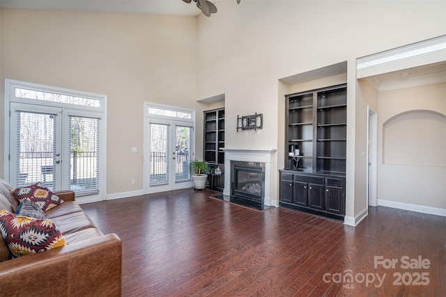 unfurnished living room with dark wood-type flooring, a high end fireplace, french doors, and a towering ceiling