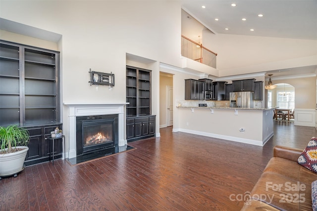 living room featuring dark hardwood / wood-style flooring, high vaulted ceiling, and built in features