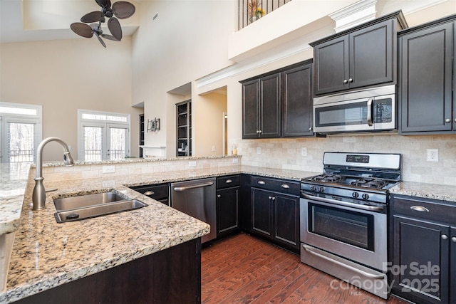 kitchen featuring dark wood-type flooring, sink, appliances with stainless steel finishes, kitchen peninsula, and decorative backsplash