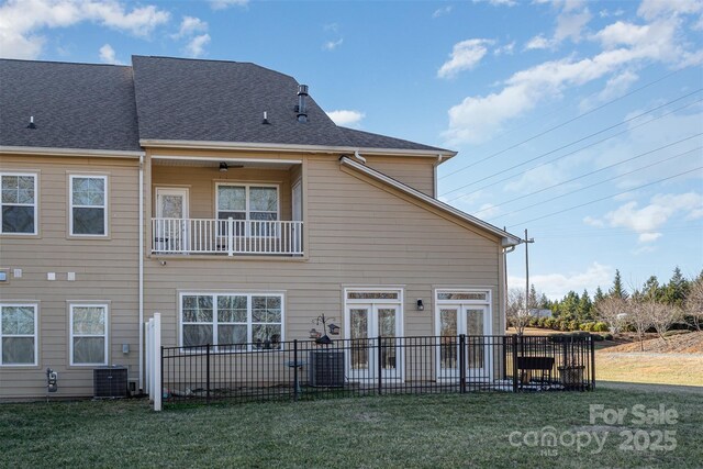 rear view of property featuring french doors, a balcony, and a lawn