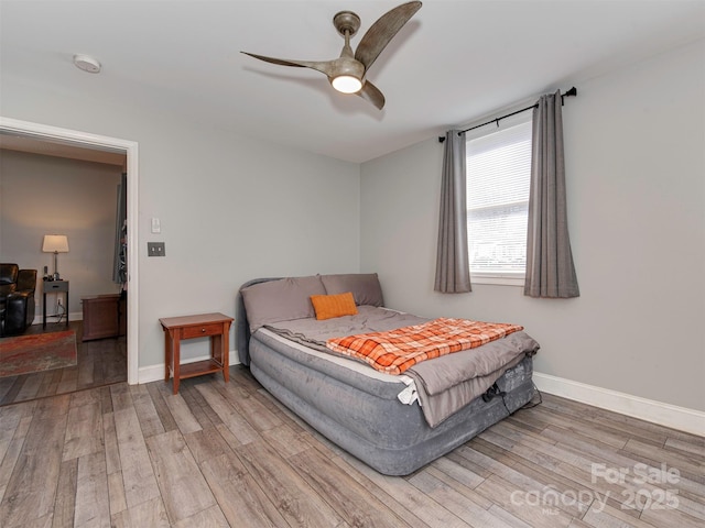 bedroom with ceiling fan, wood finished floors, and baseboards