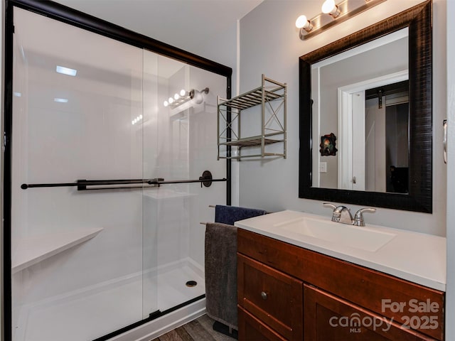 full bath with a shower stall, wood finished floors, and vanity