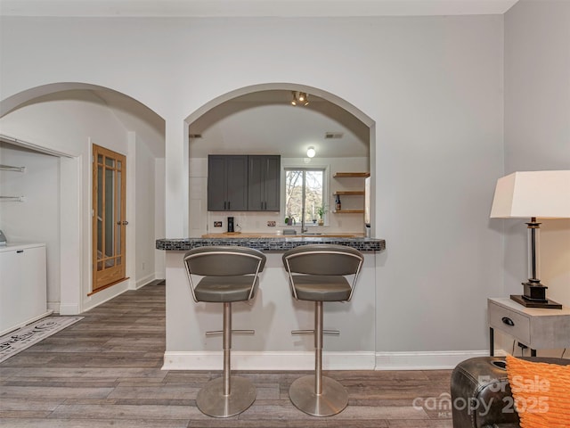 kitchen featuring independent washer and dryer, hardwood / wood-style flooring, and dark stone counters