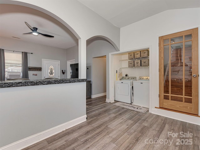 kitchen with ceiling fan, baseboards, vaulted ceiling, washer and dryer, and light wood finished floors