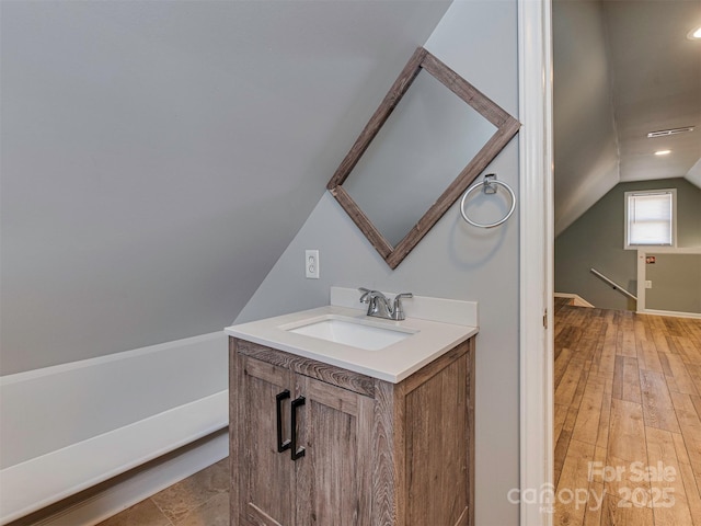 bathroom with lofted ceiling, wood finished floors, and vanity