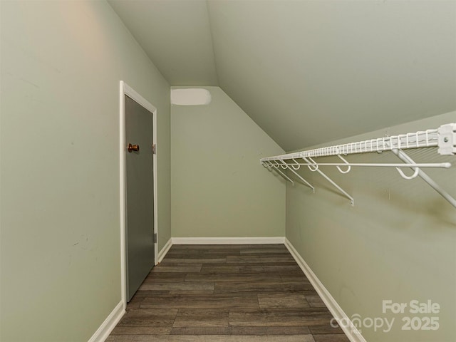 walk in closet with vaulted ceiling and dark wood finished floors