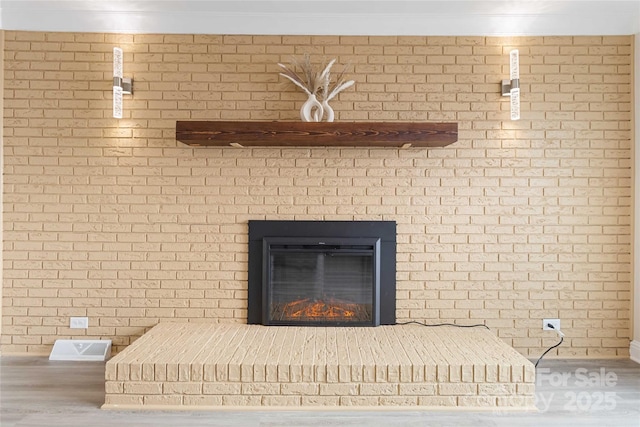 interior details with wood-type flooring, a brick fireplace, and ornamental molding