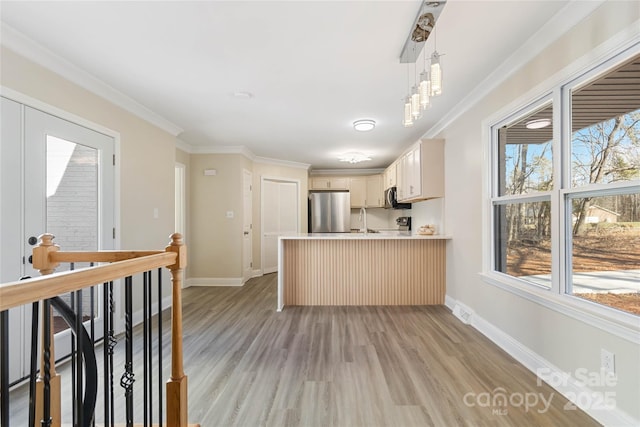 kitchen featuring crown molding, appliances with stainless steel finishes, decorative light fixtures, and kitchen peninsula