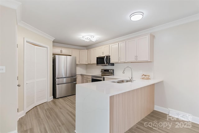 kitchen with crown molding, appliances with stainless steel finishes, sink, and light wood-type flooring