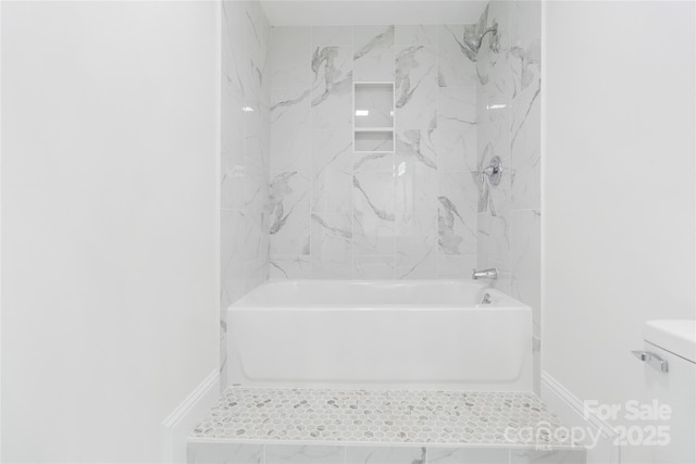 bathroom featuring tiled shower / bath and toilet