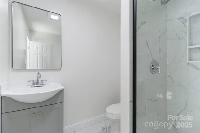 bathroom with vanity, tiled shower, and toilet