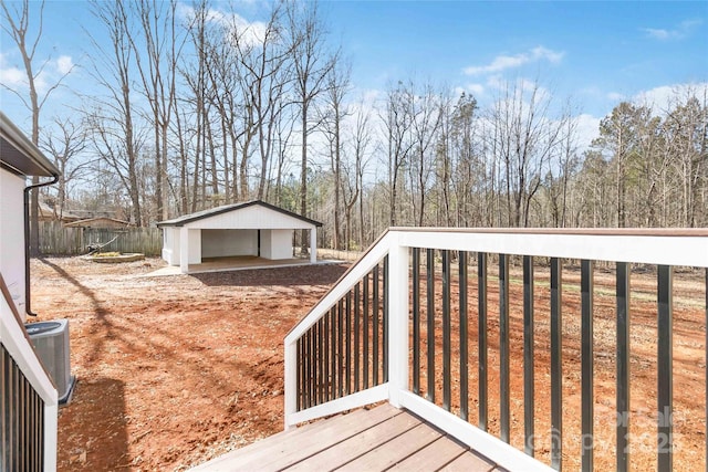 wooden terrace with a garage, an outbuilding, and central air condition unit