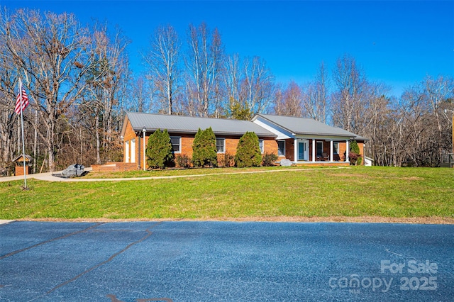 ranch-style home featuring covered porch and a front yard