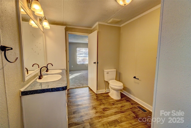 bathroom with vanity, crown molding, wood-type flooring, and toilet