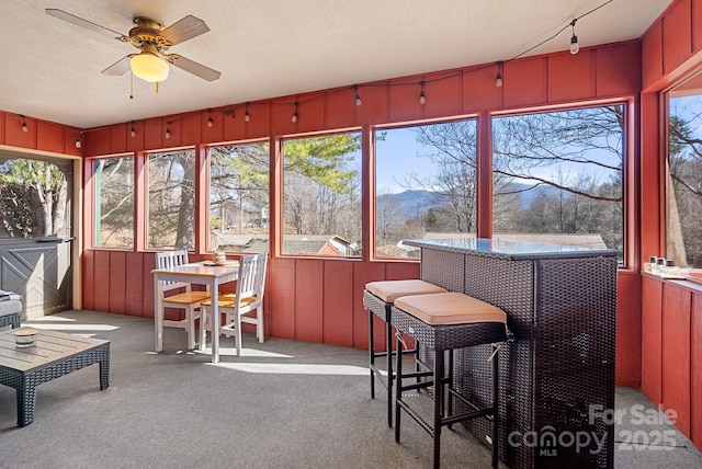 sunroom / solarium featuring a mountain view and ceiling fan