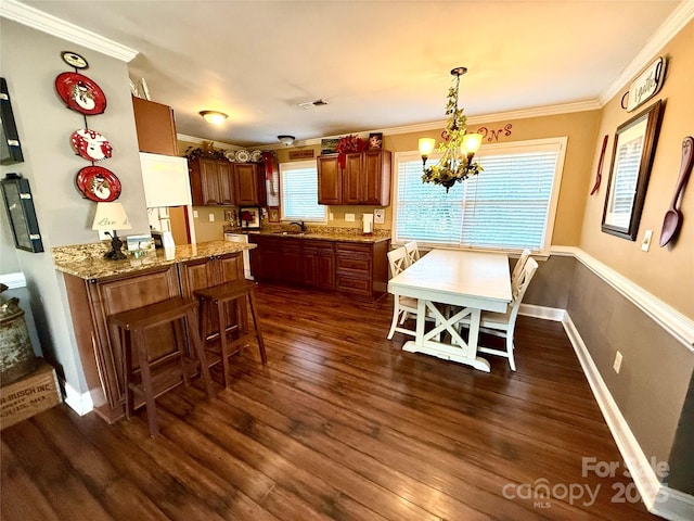 dining area featuring crown molding, dark hardwood / wood-style floors, sink, and an inviting chandelier