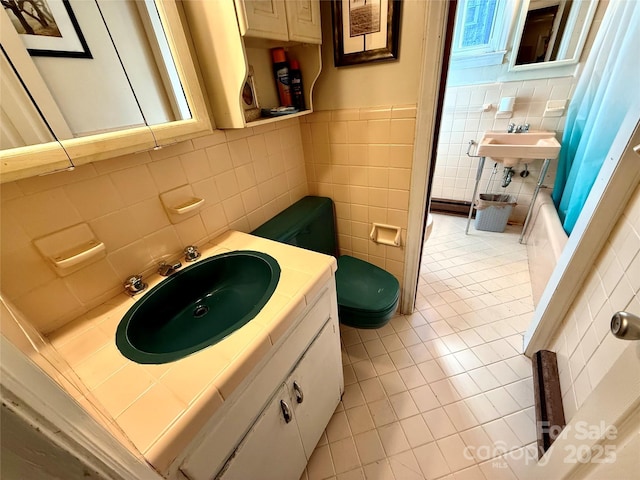 bathroom with shower / tub combo, sink, tile patterned floors, and tile walls