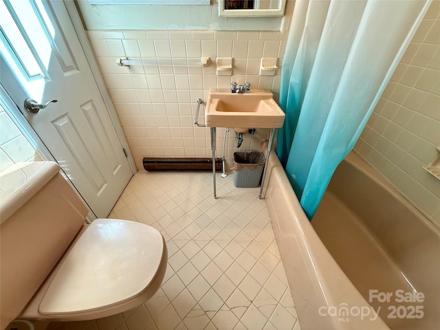 full bathroom with sink, tile walls, tile patterned floors, toilet, and shower / bath combo with shower curtain